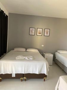 um quarto com uma grande cama branca com três fotografias na parede em Portal do Sol em Itaberaba