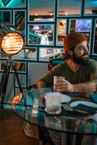 a man sitting at a table holding a glass at Aria Hotel Budapest by Library Hotel Collection in Budapest
