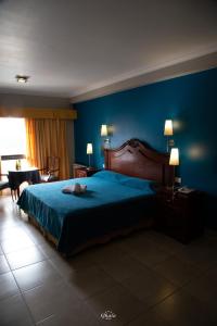 1 dormitorio con cama y pared azul en Hotel Ghala Salta en Salta