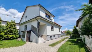 ein weißes Haus mit einem Zaun und Gras in der Unterkunft Apartmány Sebastián in Pribylina