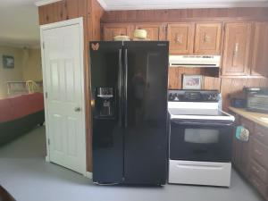 La cocina está equipada con nevera negra y armarios de madera. en The Little House at EVOO, en Cookeville