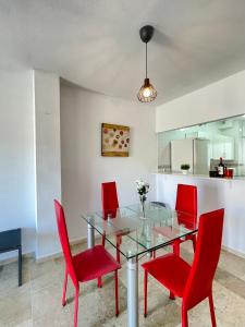 een eetkamer met een glazen tafel en rode stoelen bij LaFrenchTouch - Torrequebrada 2dorm cerca playa in Benalmádena
