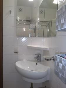 a white bathroom with a sink and a mirror at Apartments Kapus Center in Bled +54 photos