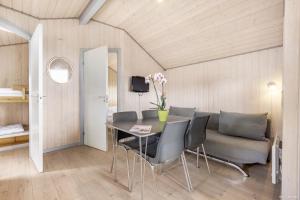 a dining room with a table and chairs and a couch at First Camp Lakolk Strand Camping in Lakolk