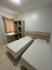 1 dormitorio con 2 camas y ventana en Vitória Hotel - Guaíra PR, en Guaíra