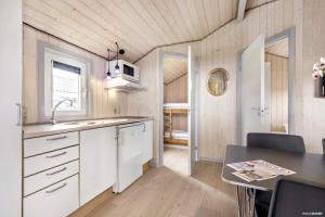 a kitchen with white cabinets and a dining table at First Camp Lakolk Strand Camping in Lakolk