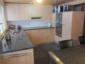 a kitchen with wooden cabinets and a counter top at Bädli im Munzenriet in Wildhaus