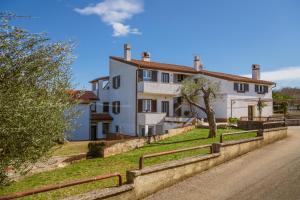 a large white house with a fence in front of it at Apartman Noli in Rakalj