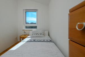 a small bedroom with a bed and a window at Apartman Noli in Rakalj