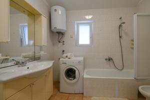 ein Badezimmer mit einer Waschmaschine und einem Waschbecken in der Unterkunft Apartman Noli in Rakalj