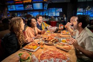a group of people sitting around a table eating pizza at SAHARA Las Vegas in Las Vegas