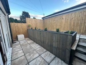 un patio trasero con una valla de madera y un patio en Nottage House Premier Apartments, en Cardiff