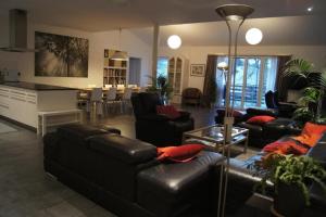 sala de estar con muebles de cuero negro y cocina en Ferienhaus "Ferme d'Alma", Wohnung "Moderne" en Ocourt