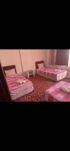 two beds in a room with pink sheets at Amkara apart hostel 5 in Altındağ