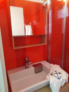 La salle de bains rouge est pourvue d'un lavabo et d'un miroir. dans l'établissement Kythnos - Loutra- House, à Loutrá
