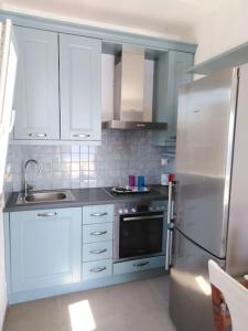 La cuisine est équipée de placards blancs et d'un réfrigérateur en acier inoxydable. dans l'établissement Kythnos - Loutra- House, à Loutrá