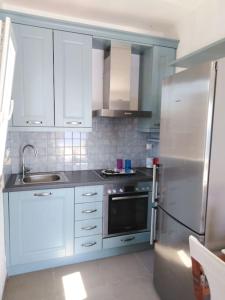 a kitchen with white cabinets and a stainless steel refrigerator at Kythnos - Loutra- House in Loutra