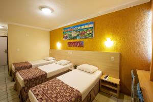 three beds in a hotel room with yellow walls at Hotel Costeiro in Olinda