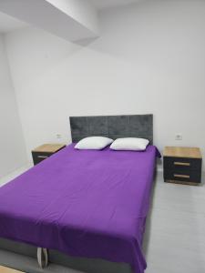 a purple bed with two pillows and two tables at Daire in Štip