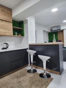a kitchen with black cabinets and white counters and white stools at Daire in Štip