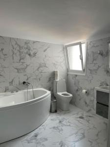 een witte badkamer met een bad en een toilet bij Sea View Condo in Chios
