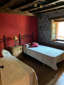 1 dormitorio con 2 camas y pared roja en CASA RURAL SIMÓN, en Soto