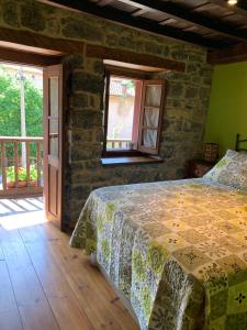 1 dormitorio con cama y pared de piedra en CASA RURAL SIMÓN, en Soto