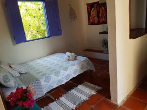 a small bedroom with a bed and a window at Chalé Flor do Ser in Canoa Quebrada
