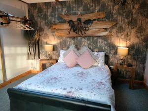 1 dormitorio con 1 cama con almohadas rosas en The Hideaway with hot tub, en Chathill