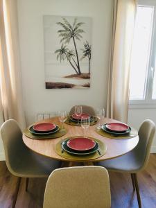 a dining room table with plates and wine glasses at Chez Louise et Lucette in Sanary-sur-Mer