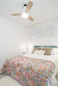 a white bedroom with a bed with a ceiling fan at Luxury Beach home in Fuengirola