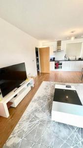 a living room with a flat screen tv and a table at Modern One Bedroom Luxury Apartment in Colindale