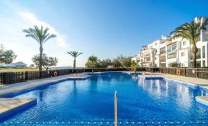 ein großer Swimmingpool mit Palmen und Gebäuden in der Unterkunft Hacienda Riquelme Golf Resort Ground Floor Apartment in Sucina