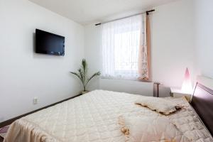 ein weißes Schlafzimmer mit einem Bett und einem TV in der Unterkunft Mónika Apartman in Remetea