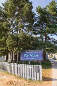 a sign in front of a fence next to a tree at Floros simfonija vilos in Šventoji