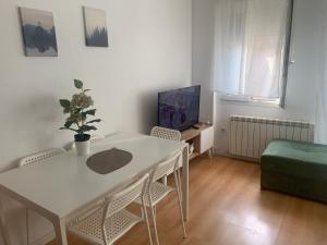 sala de estar con mesa blanca, sillas y TV en Los Seis Caños, en Madrigal de la Vera