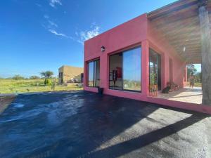 een roze huis met veel glazen ramen bij Casa Nekay in San Lorenzo