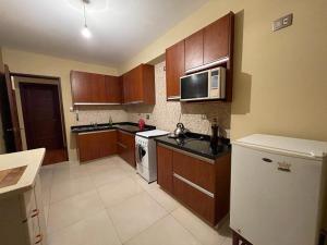 a kitchen with wooden cabinets and a white refrigerator at Departamento Lincoln Cochabamba in Cochabamba