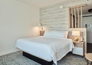 a bedroom with a white bed and a wooden wall at TownePlace Suites by Marriott Norfolk in Norfolk