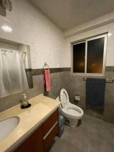a bathroom with a sink and a toilet and a window at Departamento Lincoln Cochabamba in Cochabamba