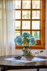 a vase with blue flowers on a table with a window at Messini Agrilia Residence in Messini