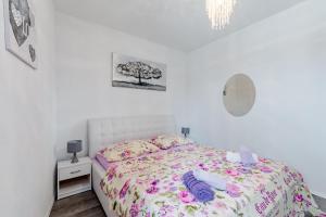 een witte slaapkamer met een bed met een bloemenbed bij Apartment Anamaris in Solin