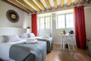 two beds in a room with red curtains at Moulin de Vilgris in Clairefontaine