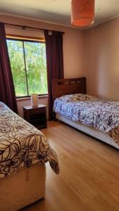 a bedroom with two beds and a window at Casa con acceso privado al río in Villarrica