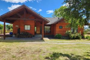 a log cabin with a porch and a yard at Casa con acceso privado al río in Villarrica