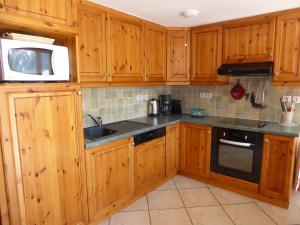 a kitchen with wooden cabinets and a sink and a microwave at Duplex Mezzanine 6 Pers. avec Grand Balcon et Garage à 400m des Commerces et Téléphérique - FR-1-464-36 in Pralognan-la-Vanoise +12 photos