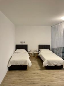Habitación con 2 camas, paredes blancas y suelo de madera. en Ferienwohnungen Valerij, en Duisburg