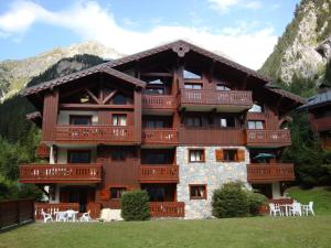 - un grand bâtiment en bois avec des chaises blanches devant dans l'établissement Appartement Pralognan-la-Vanoise, 3 pièces, 6 personnes - FR-1-464-85, à Pralognan-la-Vanoise