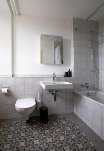 a bathroom with a sink and a toilet and a tub at Ferienwohnung Schloss Heidegg in Gelfingen