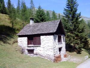 una pequeña casa de piedra al lado de una colina en Rustico Bersacola, en Bosco-Gurin